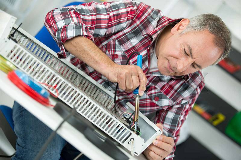 Middle-age man plumber fixing radiator, stock photo
