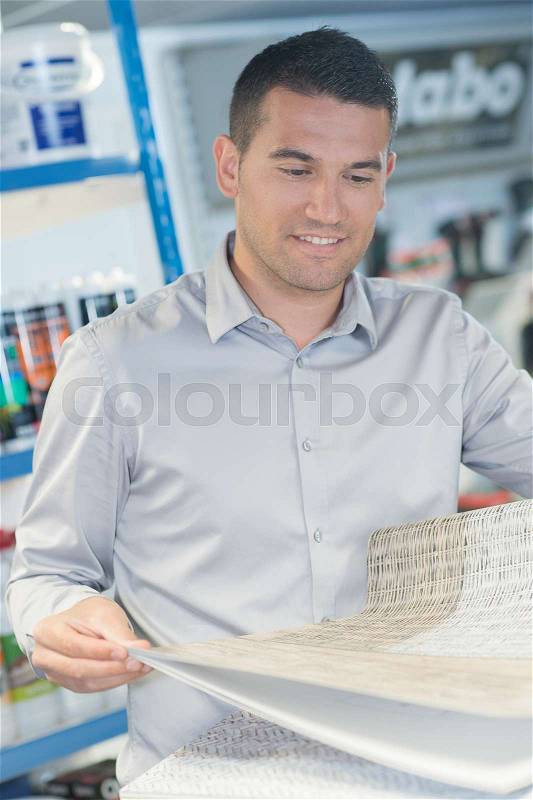 Man buying wallpaper at hardware store for do-it-yourself project, stock photo