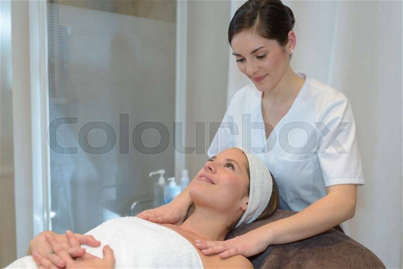 Young woman lying and having face massage in spa, stock photo