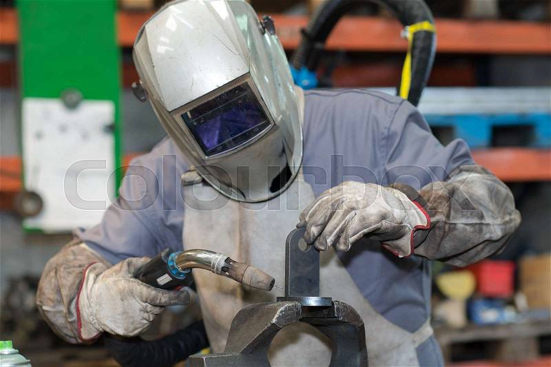 Man with welding helmet welding steel, stock photo