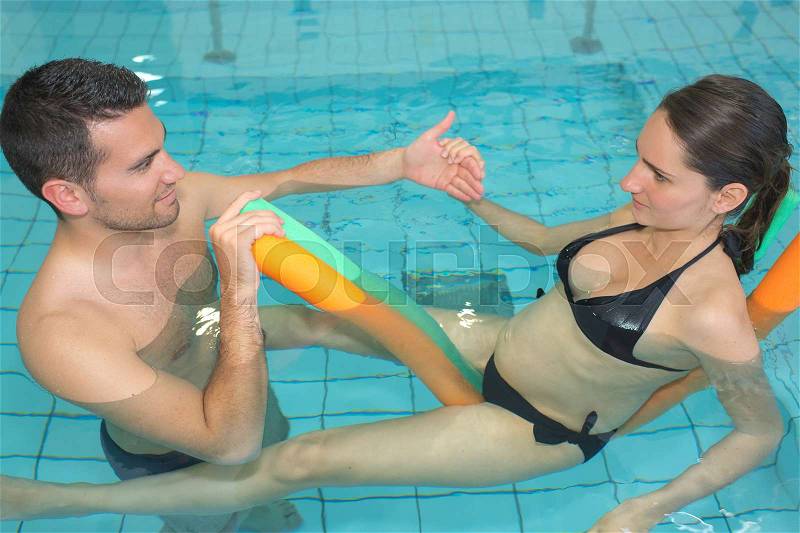 Husband and pregnant wife training at swimming pool, stock photo