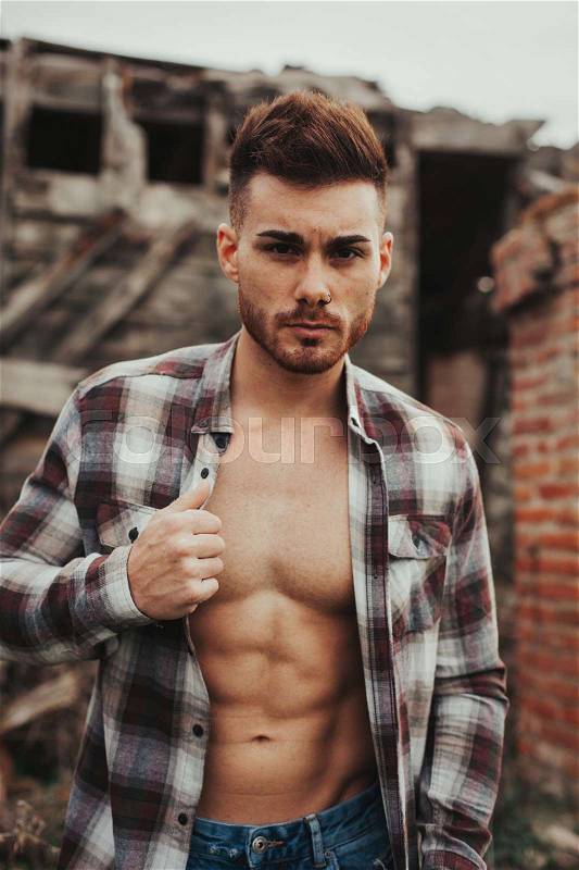 Attractive guy showing his strong chest and abs with the plaid shirt open, stock photo
