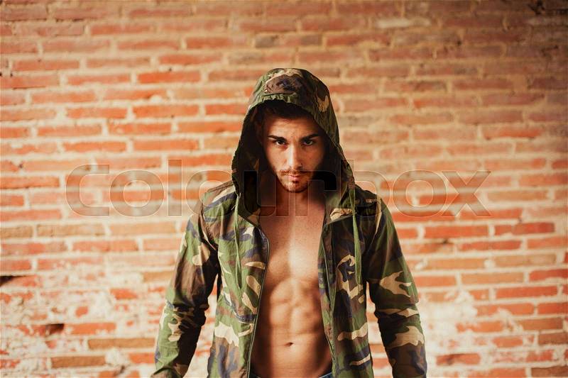 Attractive man showing his abs under a camouflage jacket, stock photo