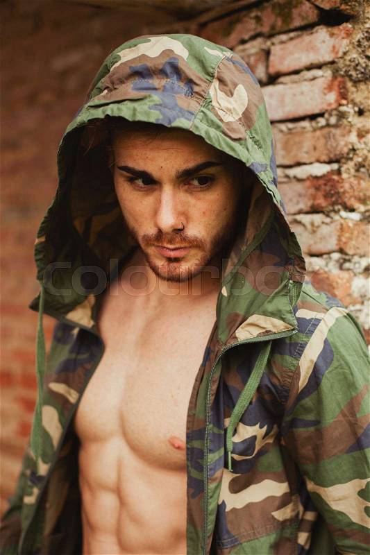 Attractive man showing his abs under a camouflage jacket, stock photo