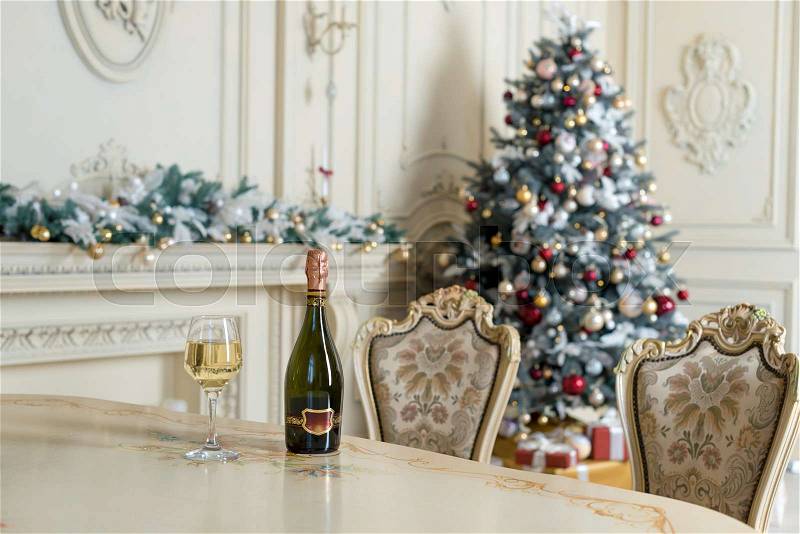 Bottle of white wine and glass on the table in beautiful holdiay decorated room for Christmas celebrations. New Year decorations, stock photo