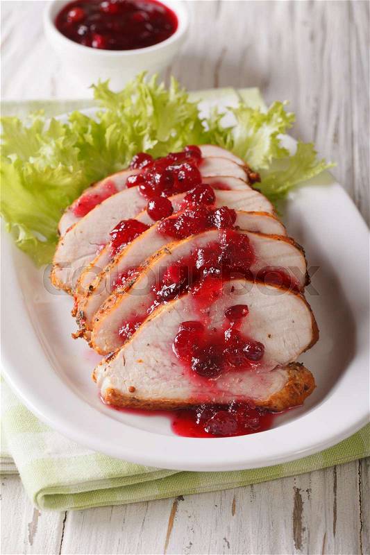 Sliced roasted turkey breast with cranberry sauce on a plate close-up on the table. vertical\, stock photo