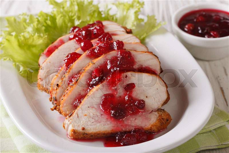 Sliced roasted turkey breast with cranberry sauce on a plate close-up on the table. Horizontal , stock photo