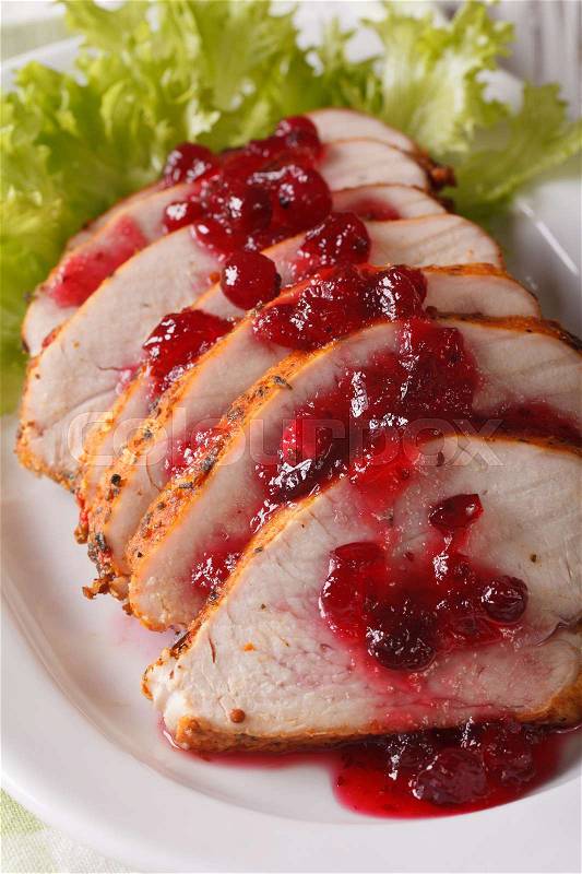 Sliced roasted turkey breast with cranberry sauce on a plate close-up. vertical\, stock photo