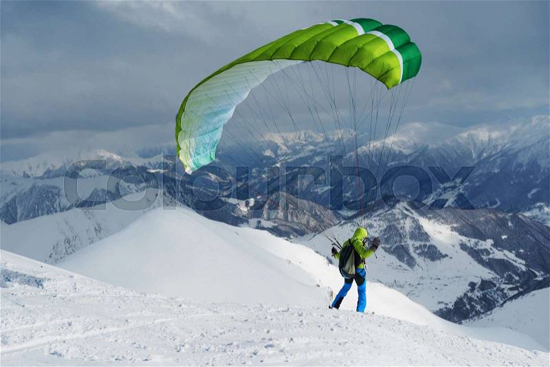 Green skier starts with a paraglider in the highlands, stock photo