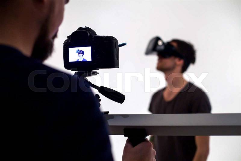 Backstage from video studio with man looking through virtual reality headset, stock photo