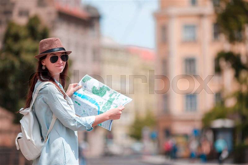Happy young woman with a city map in city. Travel tourist woman with map in Prague outdoors during holidays in Europe, stock photo