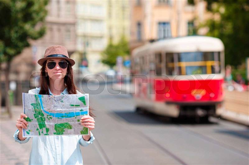 Young tourist girl with a city map searching attraction outdoors. Travel caucasian woman with map outside during holidays in Europe, stock photo