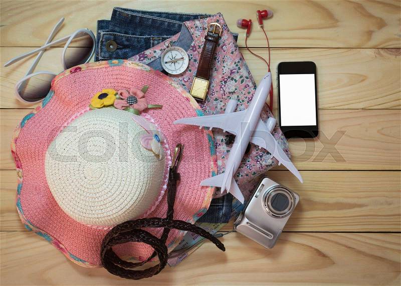 Stack of clothes and travel accessory on wooden plank. Travel concept, stock photo