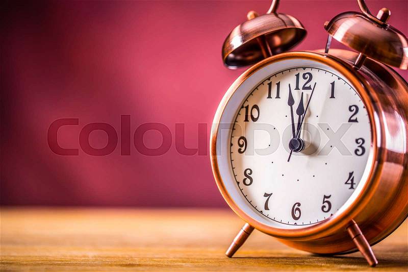 Retro alarm clock with two minutes to midnight. Filtered photo in vibrant colors 50s to 60s. Pink background, stock photo