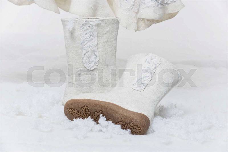 Pair of beautiful warm handmade felted boots standing on snow. Bridal winter accessory. Copy space, stock photo