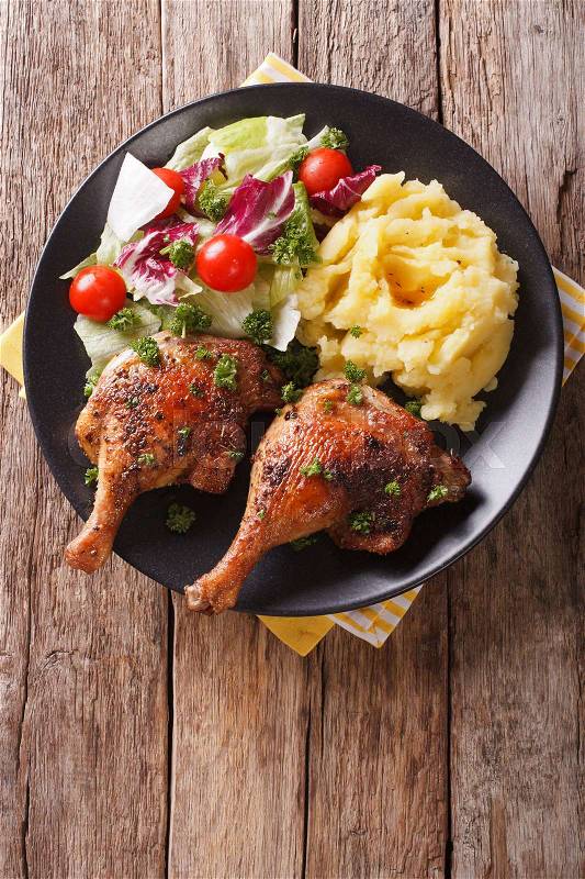 Roasted duck leg with mashed potatoes and fresh salad on the plate closeup. Vertical view from abovel\, stock photo