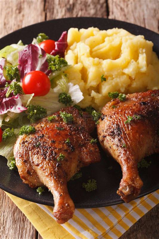 Tasty roasted duck leg with mashed potatoes and mix salad close-up on a plate. vertical\, stock photo