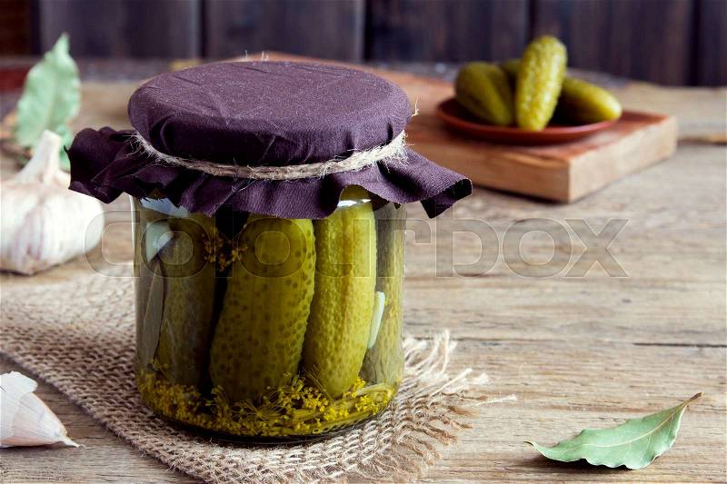 Pickles. Pickled gherkins (cucumbers) in glass jar over rustic wooden background with copy space, stock photo