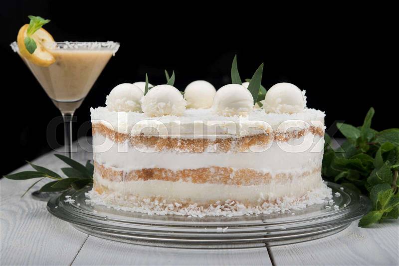Tasty coconut cake with cream vanilla balls on white wood table and black background, stock photo