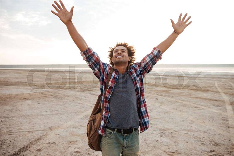 Happy man with raised hands standing on the beach, stock photo