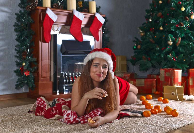 Young redhead woman with tangerines in the room with Christmas decorations, stock photo