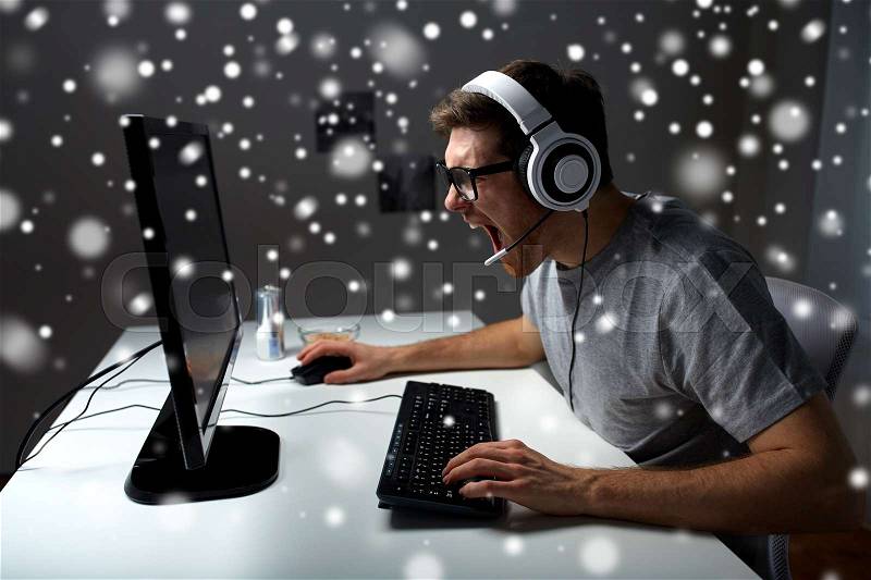 Technology, gaming, entertainment, let\'s play and people concept - angry screaming young man in headset with pc computer playing game at home and streaming playthrough or walkthrough video over snow, stock photo