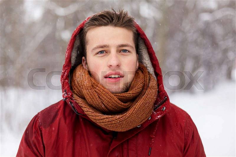 People, christmas, winter and season concept - happy man in hood and scarf outdoors, stock photo
