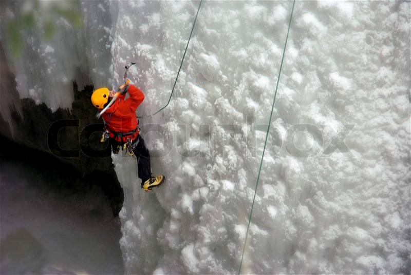 An Ice Climber going up a frozen waterfall, stock photo