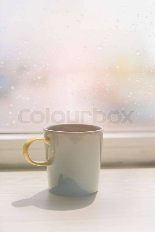 Coffee cup on table with rain drop on window background,retro effect, stock photo