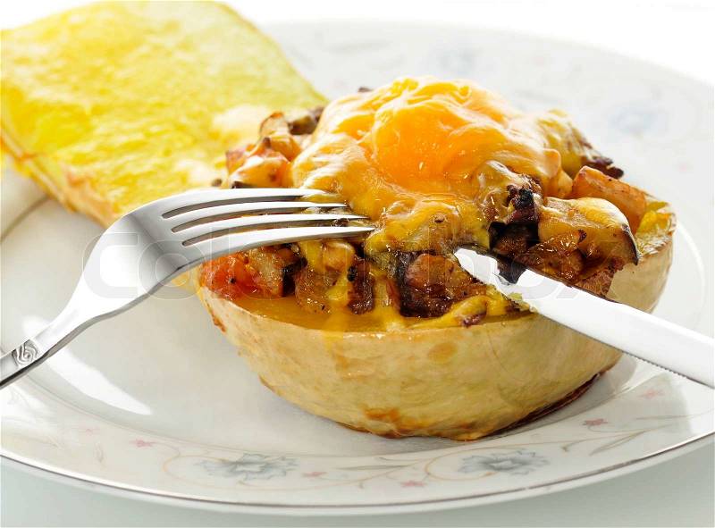 Stuffed squash with cheese on a plate with fork and knife, stock photo