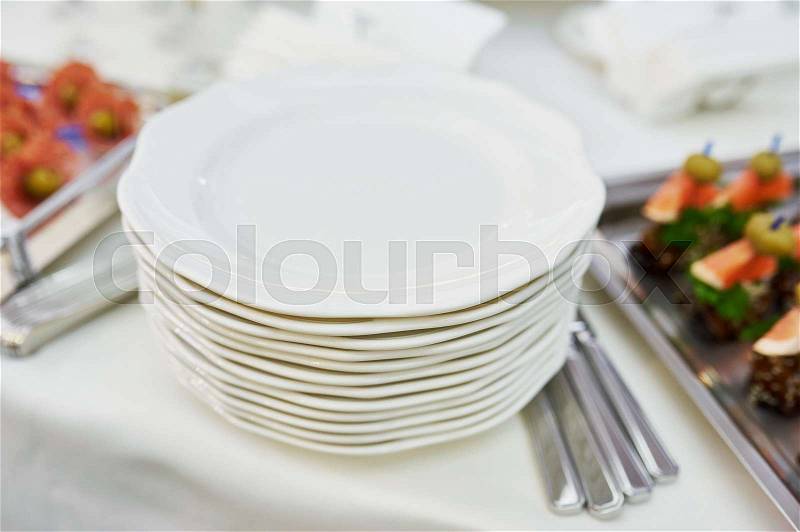 Stack of clean plates with knifes ready to be used on dinner, stock photo