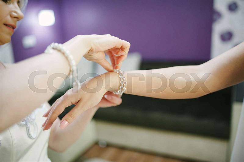 Bride getting bracelet dressed on her wedding day, stock photo
