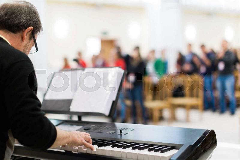 Keyboard player performing on stage live concert in front of people, stock photo