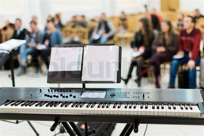 Keyboard or electric piano on stage at live concert in front of people, stock photo
