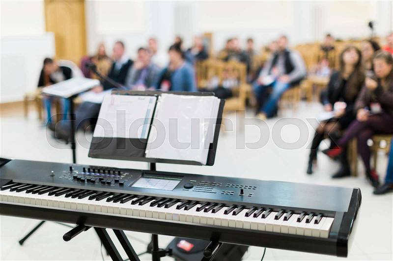 Keyboard or electric piano on stage at live concert in front of people, stock photo