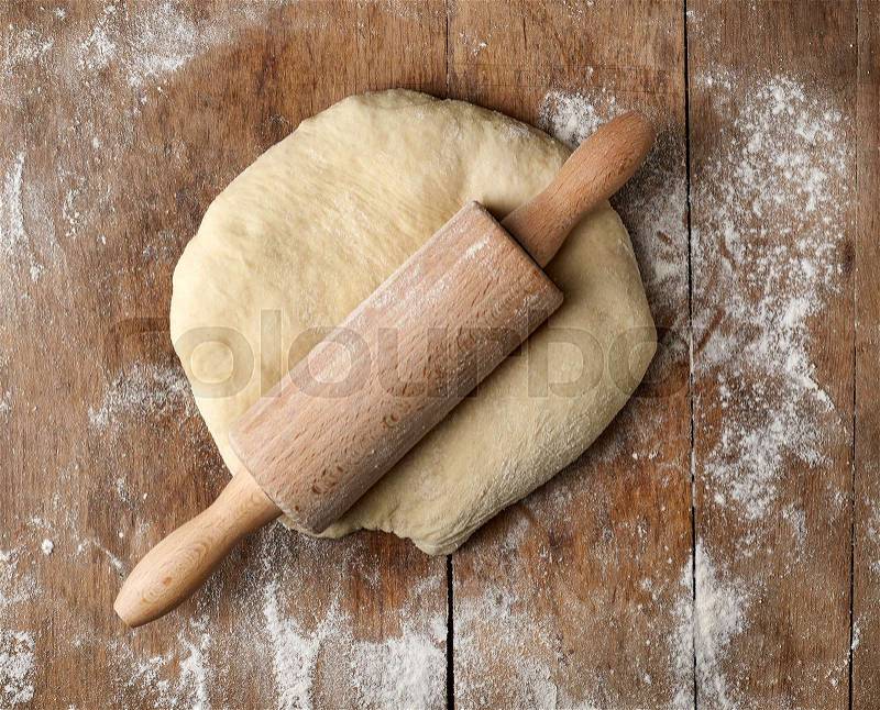 Fresh raw dough and rolling pin on rustic wooden table, top view, stock photo