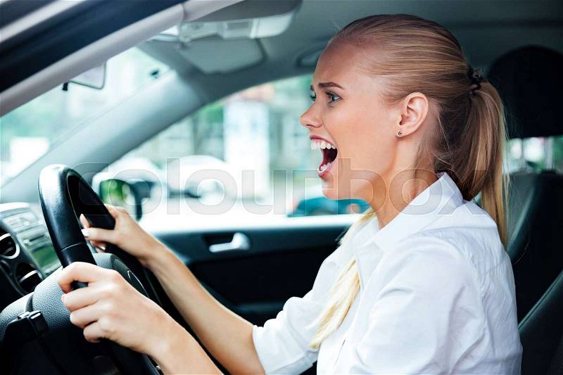 Scared business woman driving her car and shouting, stock photo