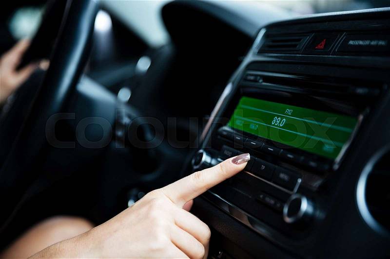 Cropped image of a woman hand turning button of radio in car, stock photo