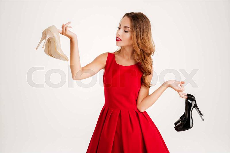 Beautiful happy woman holding high heels shoes isolated on a white background, stock photo