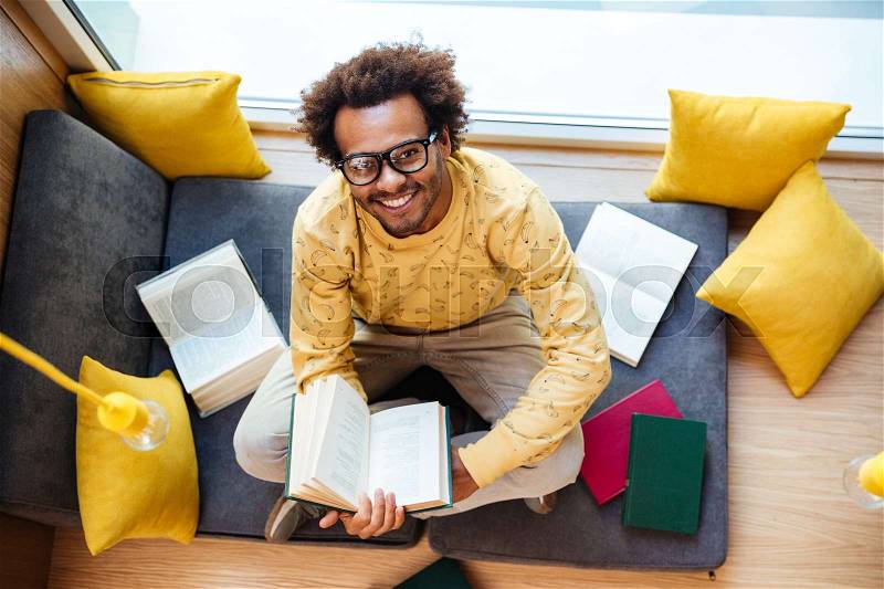 Top view of smiling african american young man with books studying at home, stock photo