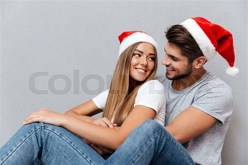 Christmas couple looking at each other\'s eyes. sitting down, stock photo