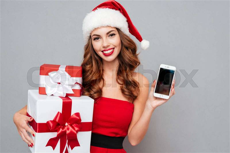 Smiling woman with gifts and phone. gifts in one hand and phone in other hand. Santa\'s helper. Dress and Santa\'s hat, stock photo