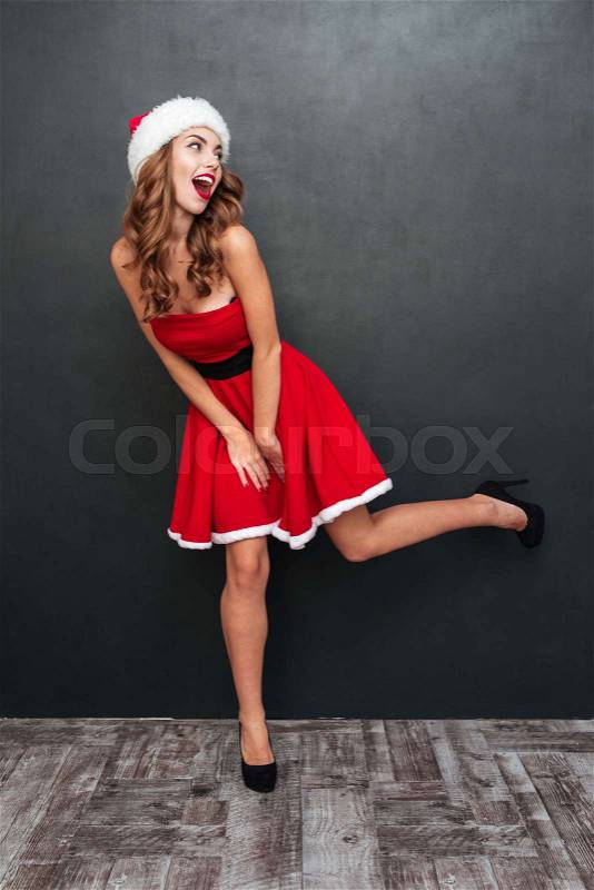 Girl with Santa hats standing on one leg. Santa's helper. Santa's dress, stock photo