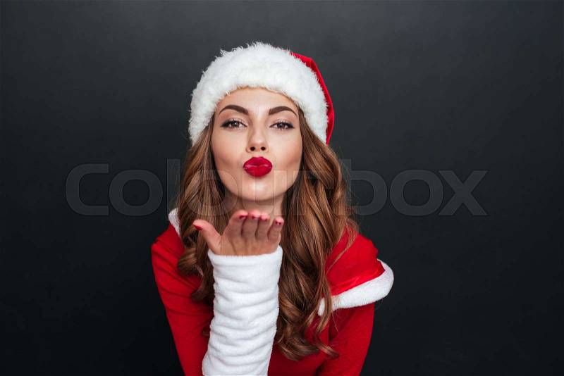 Santa\'s helper sends an air kiss over black background. Close-up, stock photo