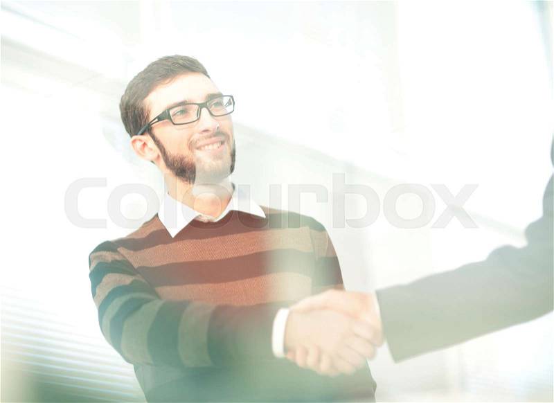 Two men shaking hands and looking at each other with smile, stock photo