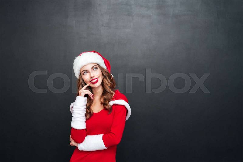 Portrait of beautiful wondered woman in red dress and hat looking away isolated on a black background, stock photo