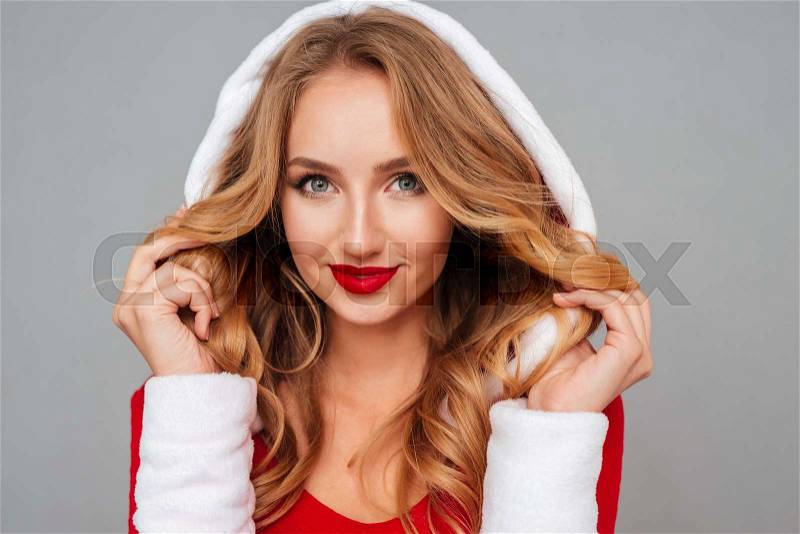Portrait of happy gorgeous young woman in santa costume over grey background, stock photo