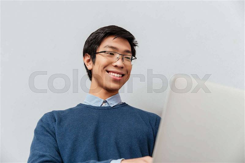 Close up asian man with laptop. smiling. gray background, stock photo