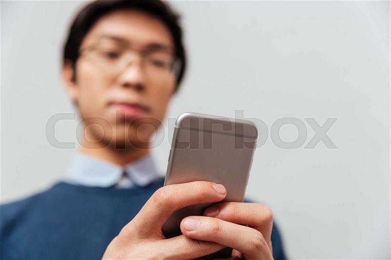 Asian man looking at the phone. gray background, stock photo
