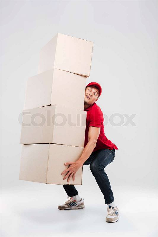 Delivery man lifts the boxes. so hard. isolated gray background, stock photo